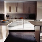 A neutral kitchen with bowls of fruit on the counters